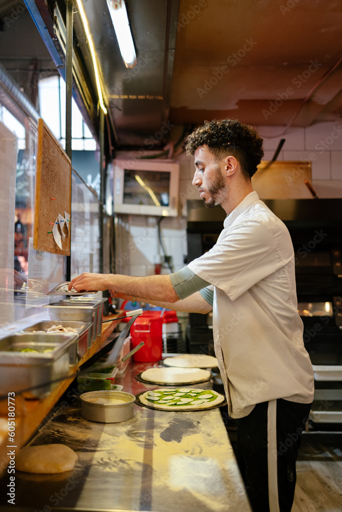 Pizza man taking ingredients from container Pizza man taking ingredients from container