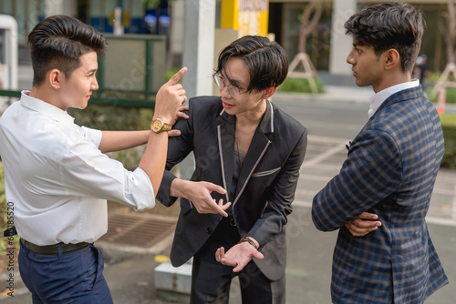 A young asian man gets in between 2 men fighting with each other and stops their quarrel. Trying to calm and reason with both people, and negotiating a truce. photo