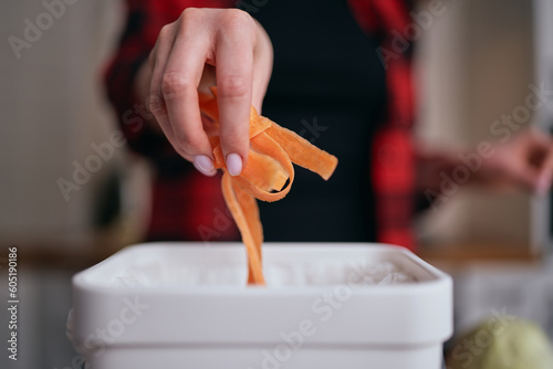 Female person throwing organic food leftovers in a bokashi bin for biological decomposition. Sustainable lifestye concept photo