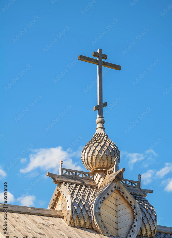 Wooden carved dome of the Orthodox Church with a cross on the sky background