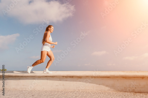 Fitness woman sea. Active, happy middle-aged woman in white sportswear exercises outdoors in a park over sea. Healthy lifestyle, physical activity and female fitness pilates and yoga routines.