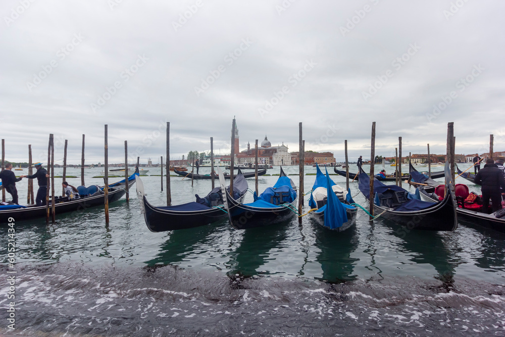 Gondolas moored at Piazza San Marco with the Church of San Giorgio di Maggiore in Venice, Italy, May 2023. Selective focus
