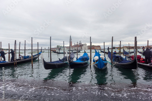 Gondolas moored at Piazza San Marco with the Church of San Giorgio di Maggiore in Venice, Italy, May 2023. Selective focus