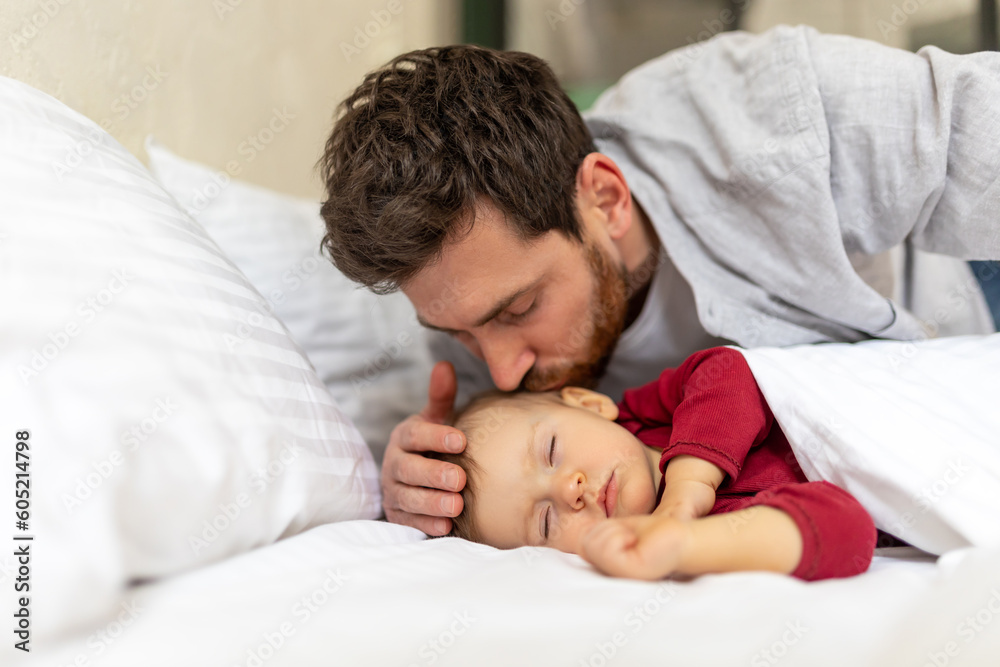 Handsome brunette father kissing sleeping infant baby tenderly. Handsome brunette father kissing sleeping infant baby tenderly.