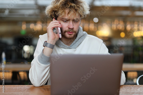 Bearded man talking on the phone while working in the office.