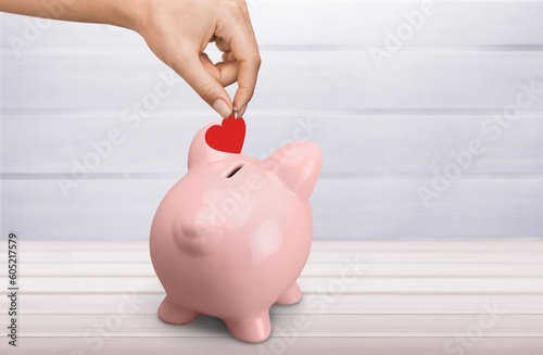 Red heart is put in a donation piggy bank