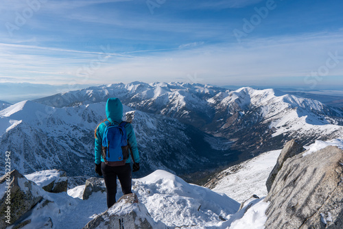 Fototapeta Naklejka Na Ścianę i Meble -  Hiker woman standing and looks around, admiring winter mountain landscape. Happy tourist woman in winter. High Tatras, 1987 meter above sea level. Slovakia