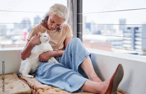 Senior woman relax with her cat on home floor for mental health, wellness or emotional support, love and care. Elderly person in retirement scratch or cuddle pet, animal or kitten by house or window photo