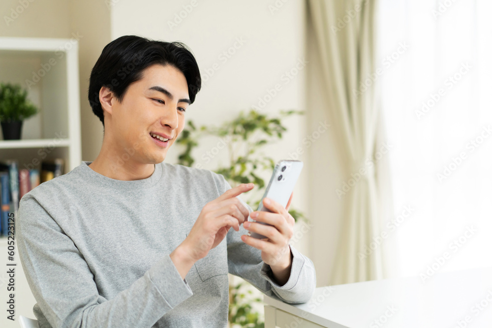 自宅で携帯電話を使用している日本人男性