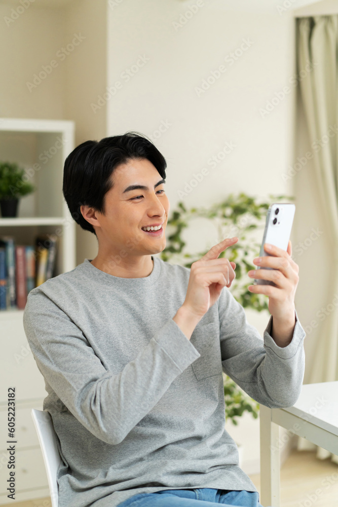 自宅で携帯電話を使用している日本人男性 自宅で携帯電話を使用している日本人男性