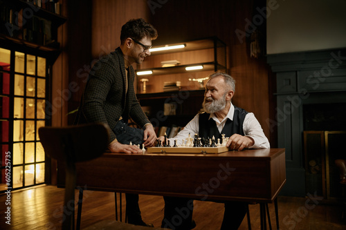 Happy intelligent family playing chess spending time together at home library