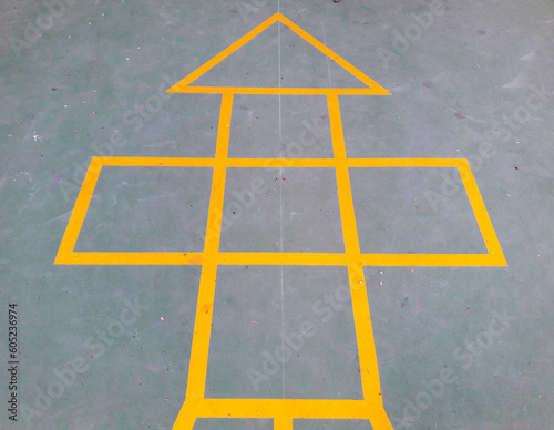 Painted yellow lines contrast against the dark asphalt and form the classic school playground game of Hopscotch photo