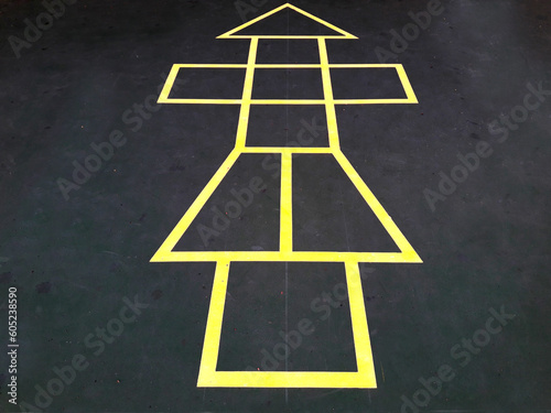 Painted yellow lines contrast against the dark asphalt and form the classic school playground game of Hopscotch photo
