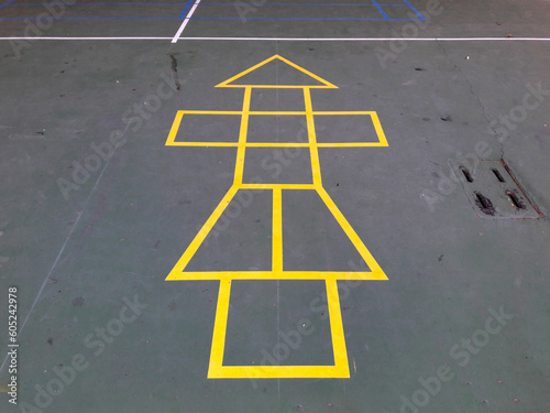 Painted yellow lines contrast against the dark asphalt and form the classic school playground game of Hopscotch photo