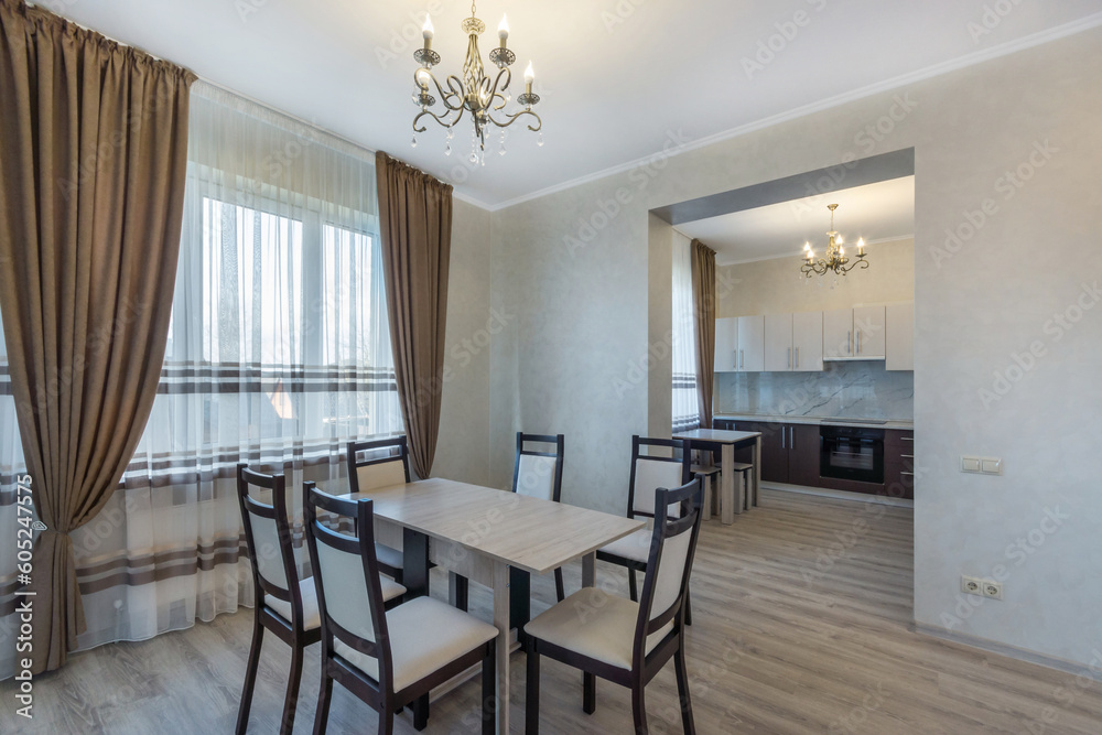 The interior of the dining room and kitchen in a country house. Elegant furniture, .beautiful curtains and tulle on the window. The interior of the dining room and kitchen in a country house. Elegant furniture, .beautiful curtains and tulle on the window.