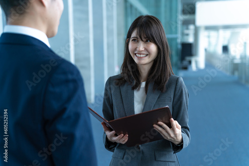 室内で話をするスーツを着た日本人男女