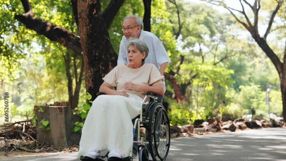 Happy Asian senior man pushing a wheelchair for wife outside in the park, Senior couple and retirement life concept Happy Asian senior man pushing a wheelchair for wife outside in the park, Senior couple and retirement life concept