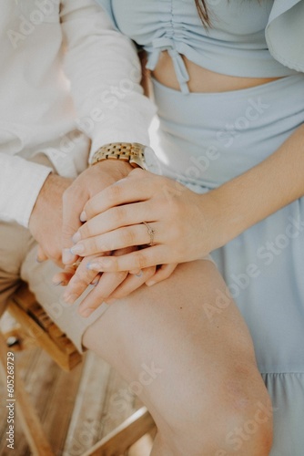 Vertical closeup shot of an engaged female holding her hands over her fiances hands photo