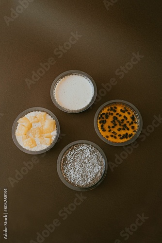 Vertical shot of plastic bowls of various creamy pudding on a brown surface