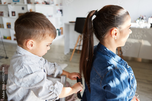 Little boy combs his mother s long hair