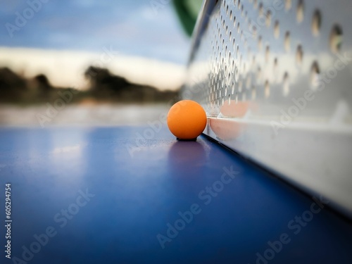 Vibrant orange table tennis ball on a blue table