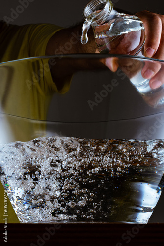 Closeup of a male pouring clean water into a glass bowl photo