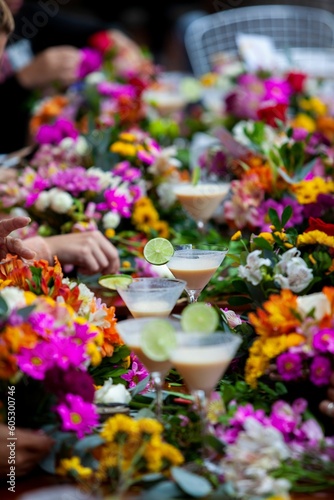 a long table topped with flowered vases filled with alcoholic drinks