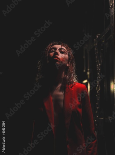 Vertical dramatic shot of a young female with red bloody face paint and a red suit