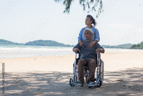 Wallpaper Mural Happy Asian senior man on wheelchair and elderly woman couple smiling on sand of the beach for taking the patient travel together Torontodigital.ca
