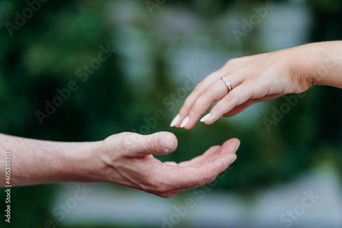Female hand with a wedding ring touching the male fingers © Airah Mei/Wirestock Creators