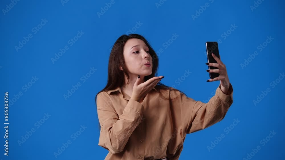 4k video of one girl who talking to someone on a video call over blue background. 4k video of one girl who talking to someone on a video call over blue background.