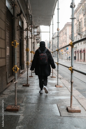 a woman in a black jacket is walking on the sidewalk