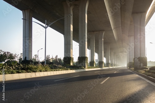 Road under a highway in sunlight