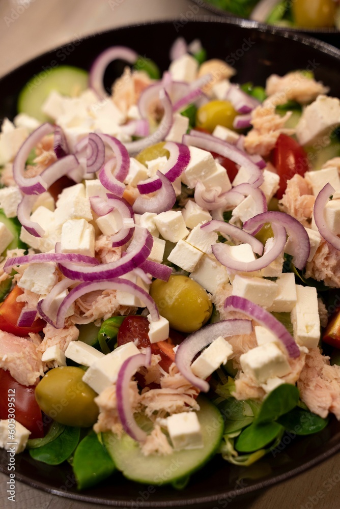 Healthy and balanced bowl of salad featuring diced red onions, green olives and juicy tomatoes