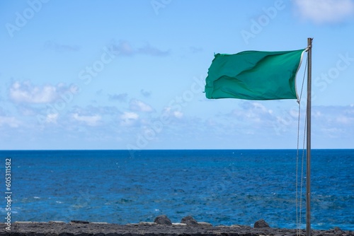 Closeup of a green flag at the coastline