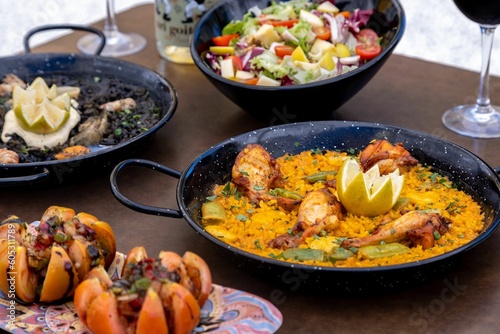 Closeup of Paella and Arros negre served with vegetable salad in a restaurant