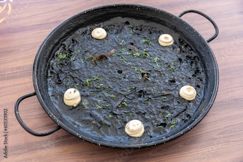 Top view of delicious Arros negre dish on wooden table photo