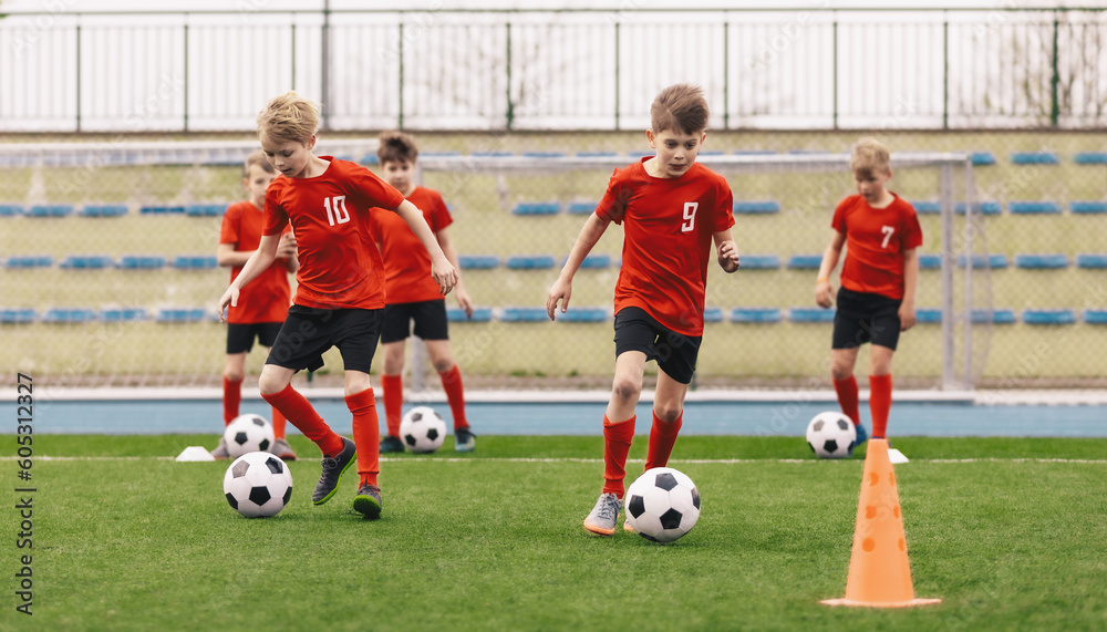 Young Boys at Soccer Training. Group of School Kids Kicking Soccer Balls During Practice Session. Children Improving Football Dribbling Skills Kicking Balls Between Cones Young Boys at Soccer Training. Group of School Kids Kicking Soccer Balls During Practice Session. Children Improving Football Dribbling Skills Kicking Balls Between Cones