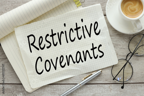 Restrictive Covenants On a wooden background, a notepad with text with a cup of coffee and glasses photo