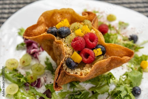 Closeup shot of a gourmet taco salad dish with raspberries, blueberries, and salad