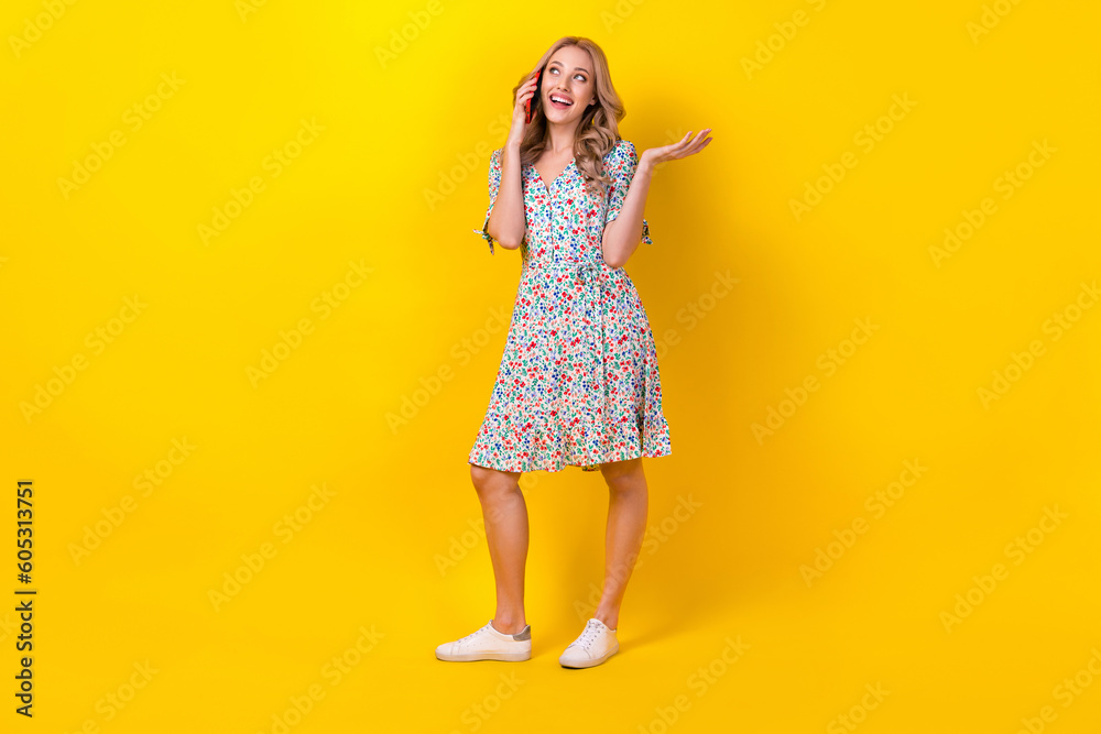 Full length photo of sweet dreamy lady wear flower print dress talking modern gadget empty space isolated yellow color background Full length photo of sweet dreamy lady wear flower print dress talking modern gadget empty space isolated yellow color background