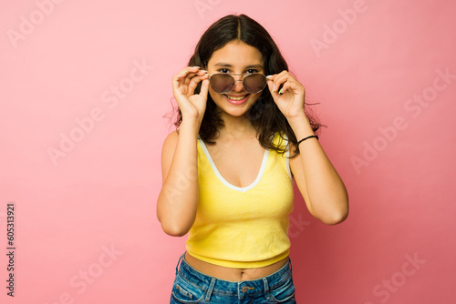 Adorable teenager putting on summer sunglasses