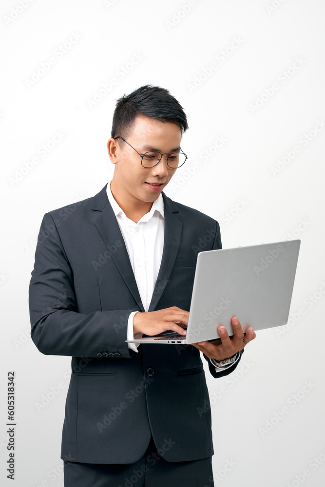 Portrait of smiling handsome young businessman in formal suit holding an open laptop in hand Portrait of smiling handsome young businessman in formal suit holding an open laptop in hand