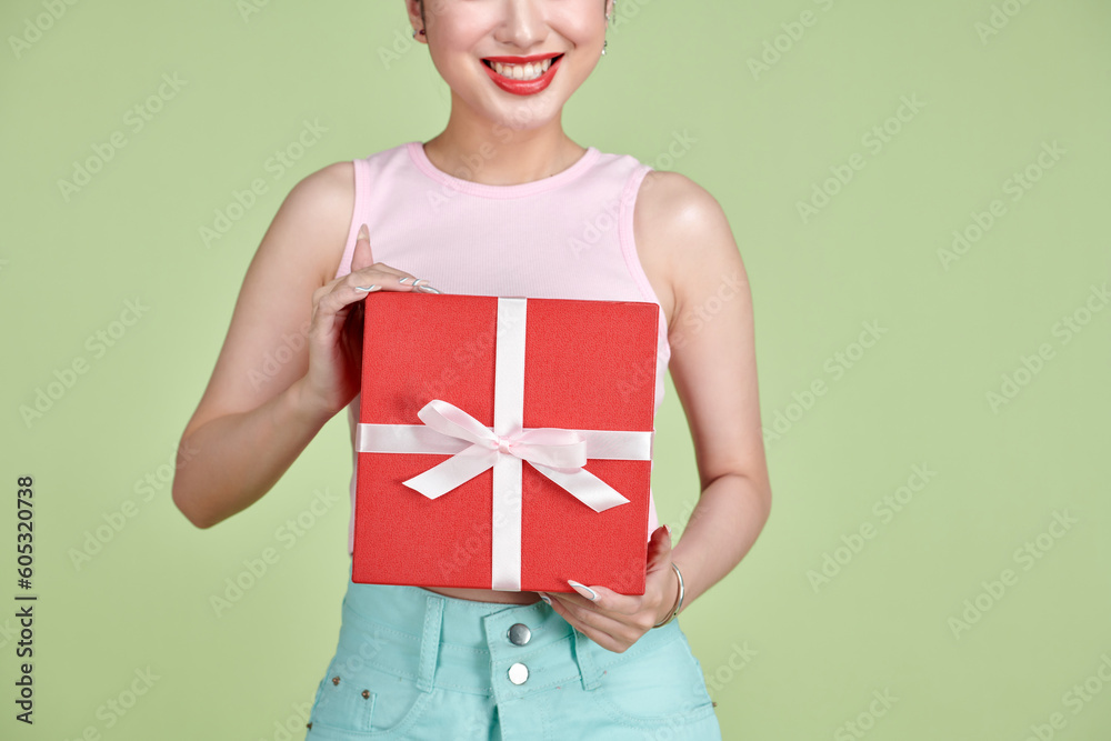 Happy pretty young woman holding gift box over green background Happy pretty young woman holding gift box over green background