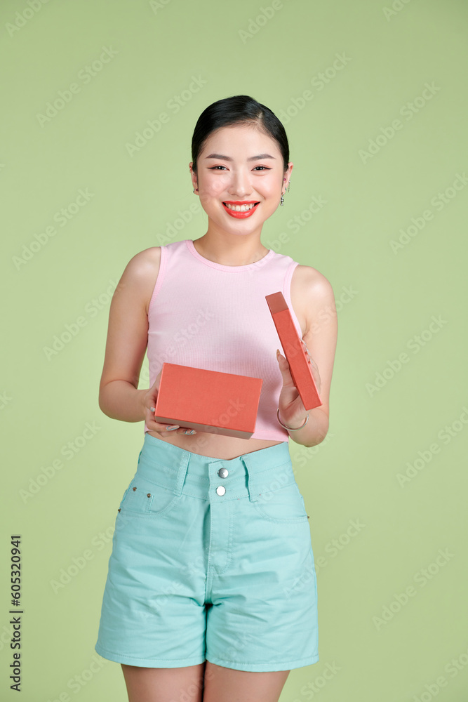 Cheerful young woman opening present box isolated on a white background Cheerful young woman opening present box isolated on a white background