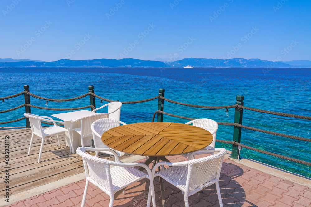 Empty cafe with chairs and tables by the seafront under a blue sky in summer.