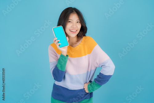 Beautiful young woman smiling happily while holding a Smartphone in her hand