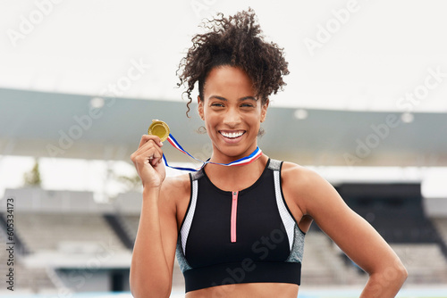 Happy woman, fitness and portrait smile with gold medal for winning, athletics or running competition at stadium. Fit and active African female person, runner or winner smiling with award in victory © Emil L/peopleimages.com