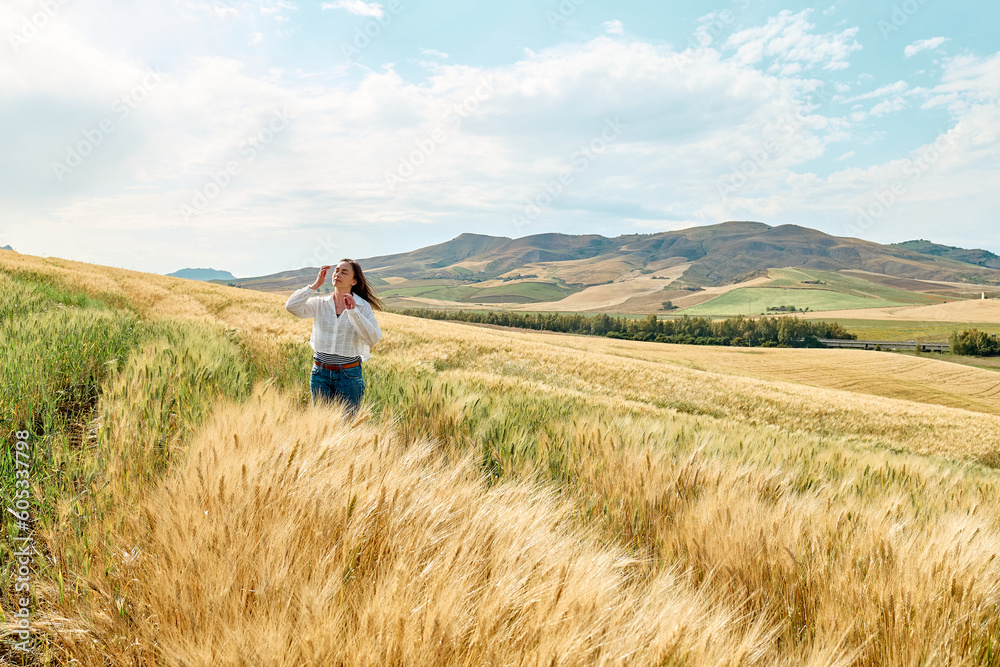 Woman walking in golden wheat field in hot summer sun and blue sky with white clouds with mountains hill landscape in background. Woman walking in golden wheat field in hot summer sun and blue sky with white clouds with mountains hill landscape in background.