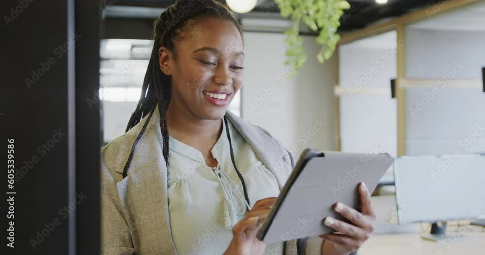 Happy african american casual businesswoman using tablet standing in office, slow motion Happy african american casual businesswoman using tablet standing in office, slow motion